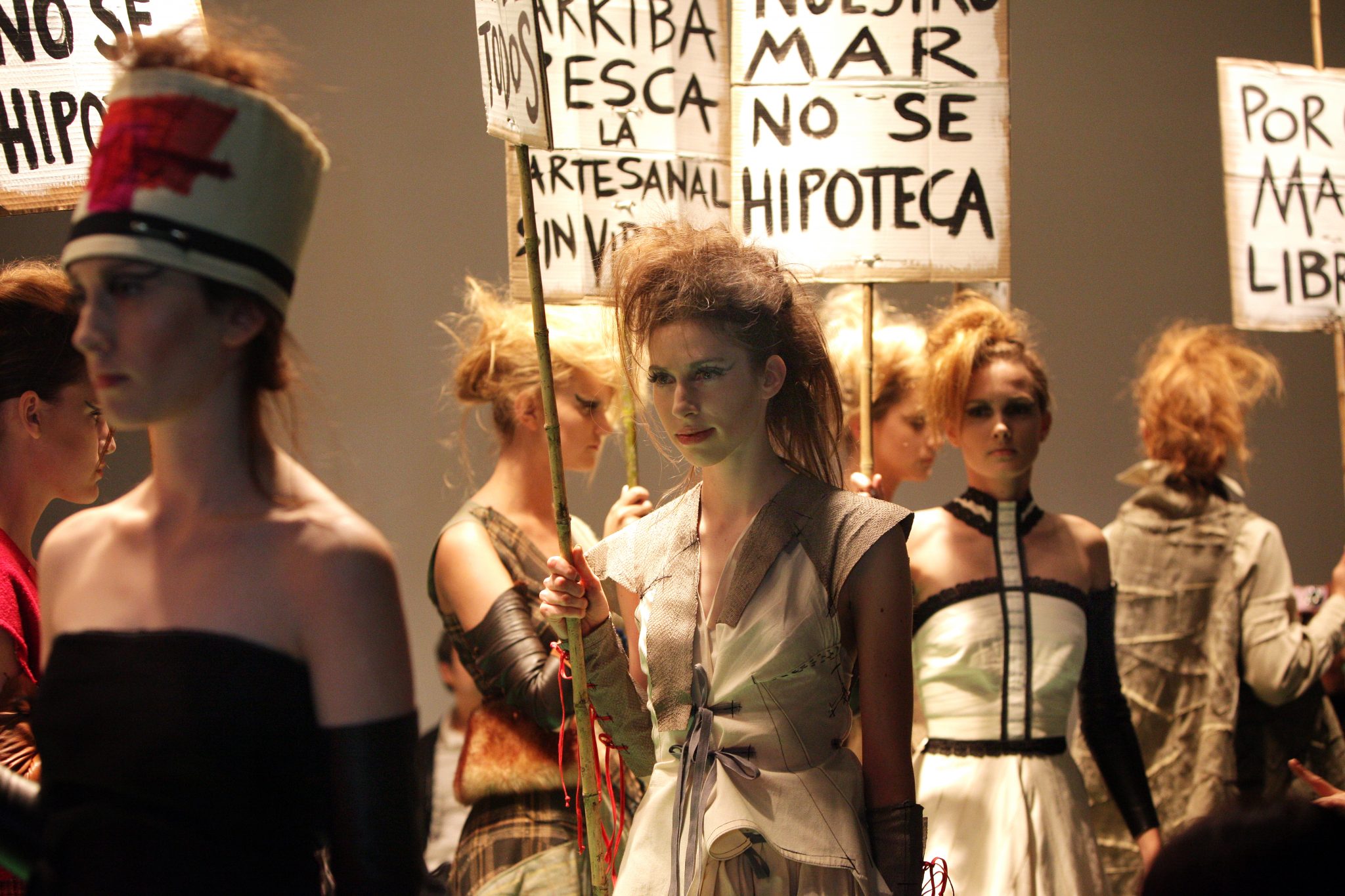 personas en un desfile de moda portando carteles