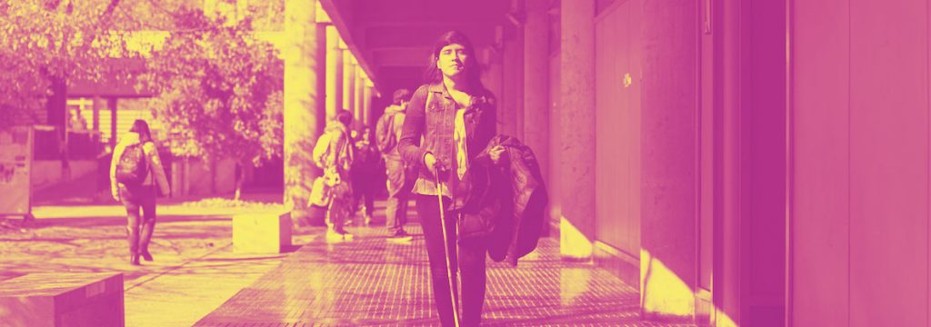 mujer en Situación de Discapacidad caminando por el campus san joaquín de la UC